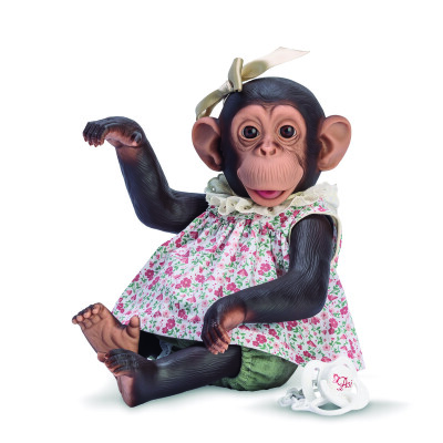 Boneco de macaco vestido com vestido floral e laço, ao lado chupeta branca.