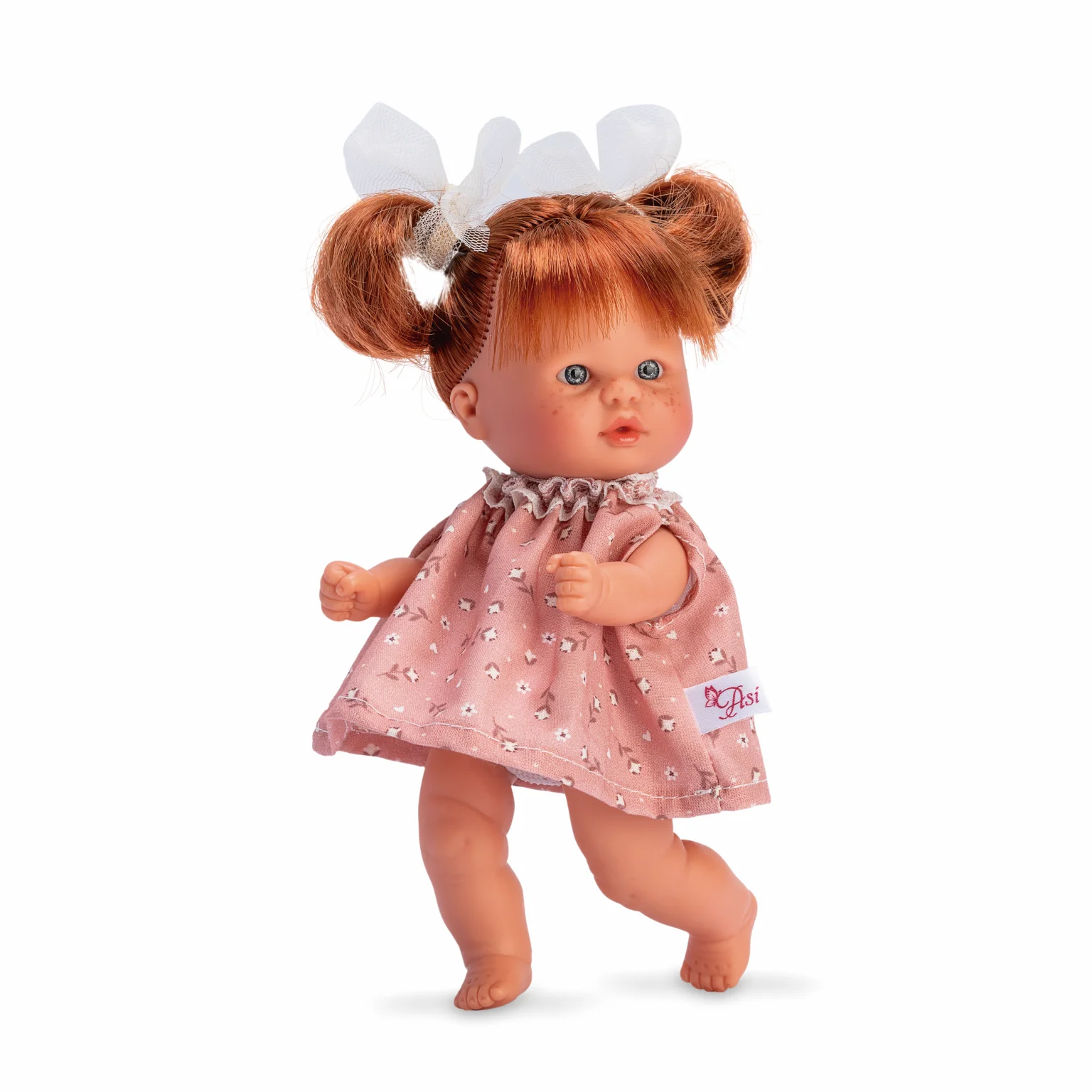 Boneca de plástico com vestido rosa e laços brancos no cabelo