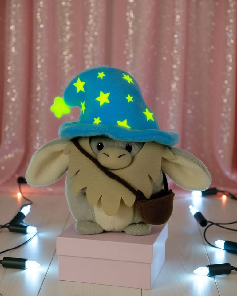 Pelúcia com chapéu azul com estrelas amarelas sobre caixa rosa e luzes brancas
