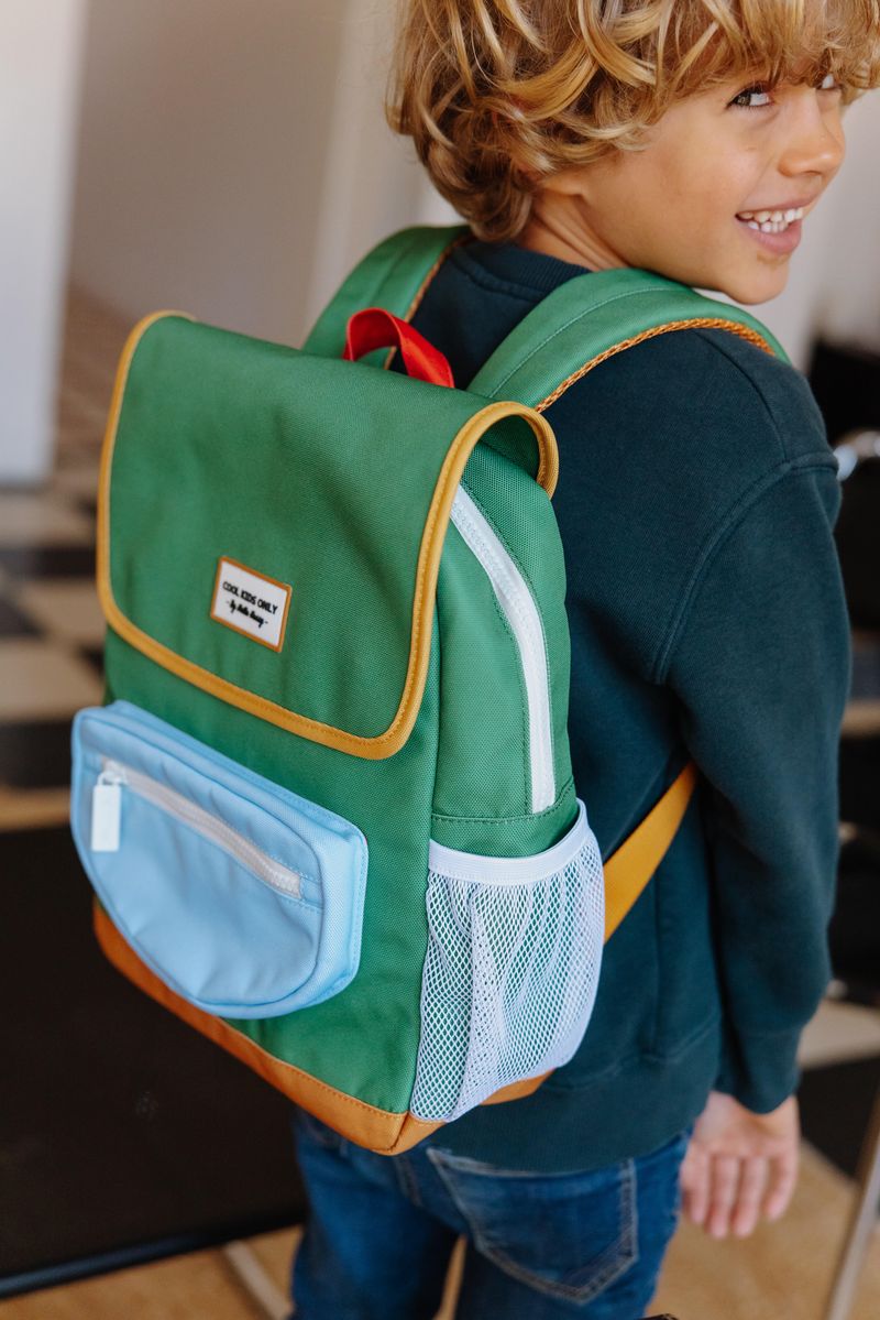 Criança com mochila verde com bolso azul claro e detalhes amarelos