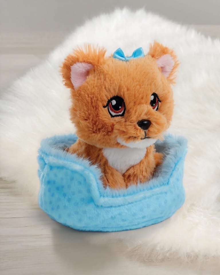 Peluche de gatinho castanho claro numa cama azul felpuda