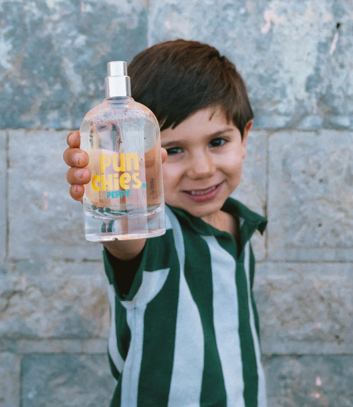 Menino a segurar garrafa spray transparente com texto amarelo e azul