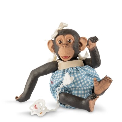 Boneca chimpanzé com vestido azul aos quadrados e fita na cabeça, com chupeta branca