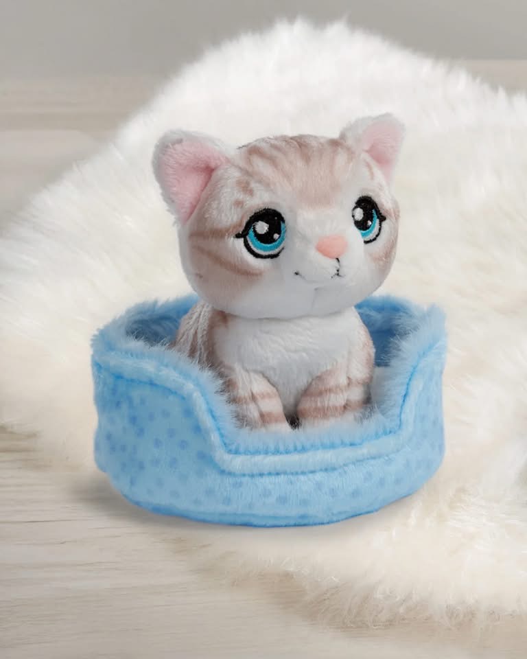 Pelúcia de gato bege e branco numa cama azul clara macia