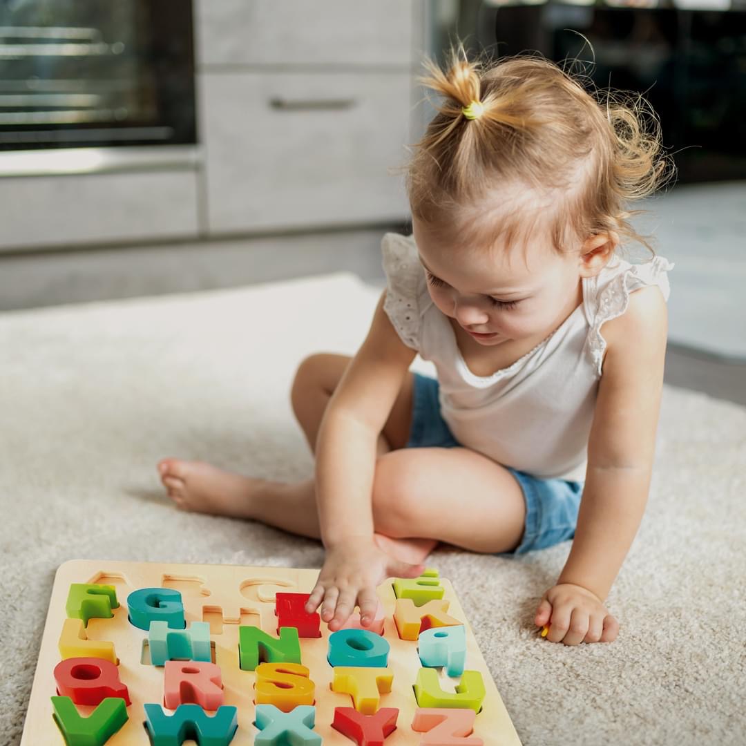 Criança a brincar com puzzle de letras de madeira coloridas