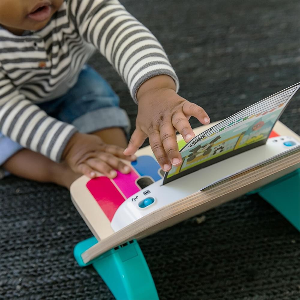 Bebé a brincar com brinquedo educativo de madeira colorido sobre tapete preto