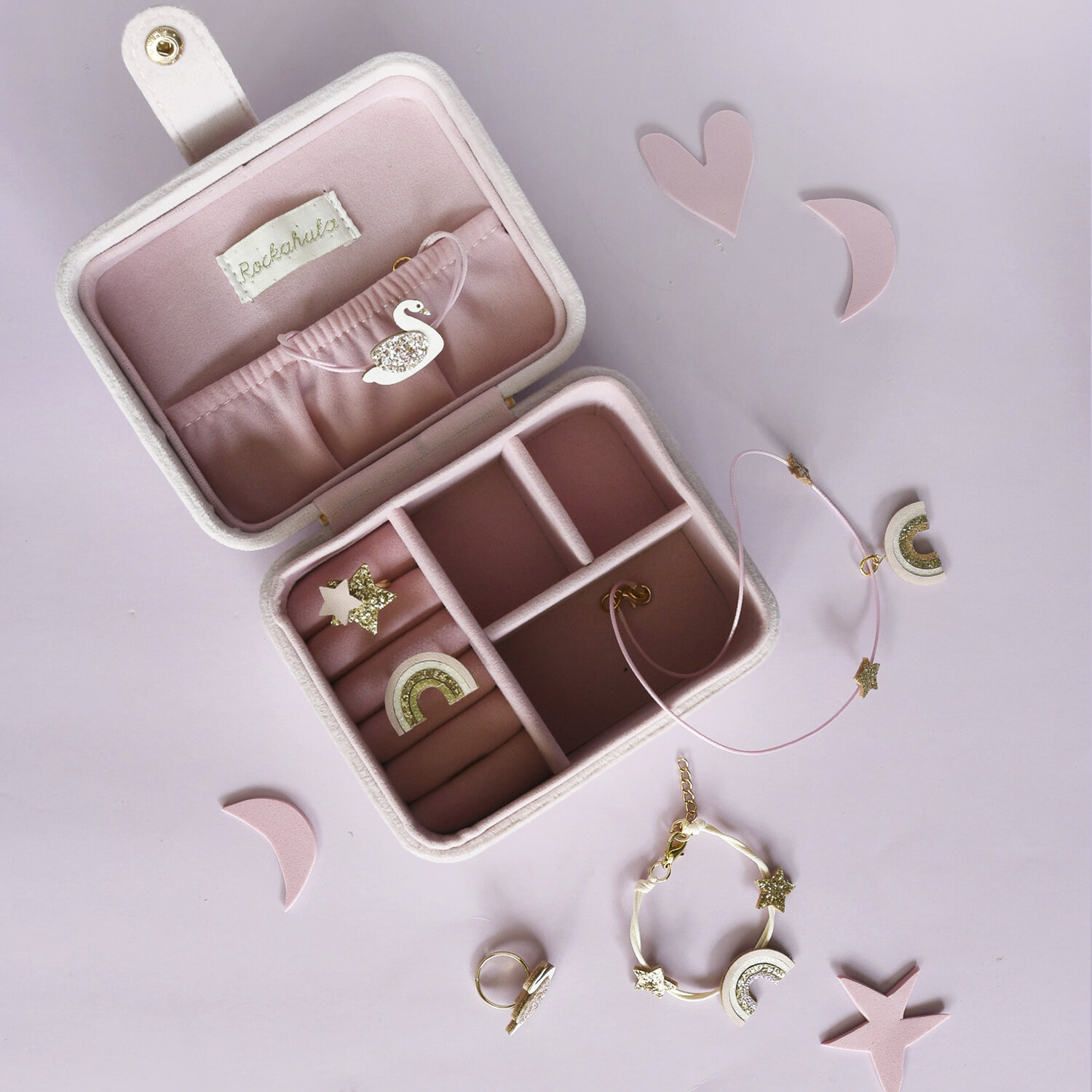 Estojo de joias rosa claro com joias e pendentes de estrela e arco-íris