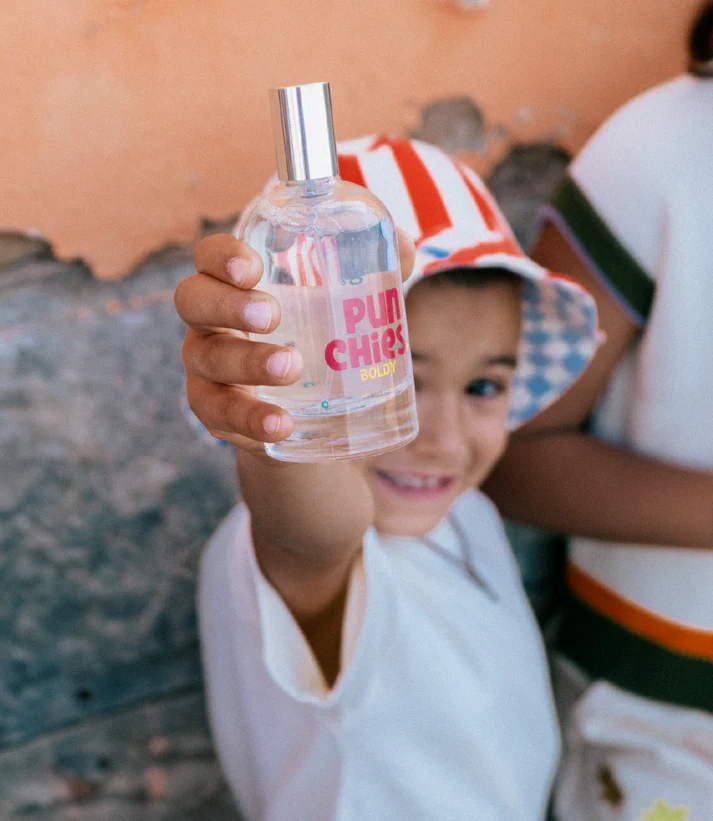 Garoto segurando frasco de perfume transparente com tampa prateada