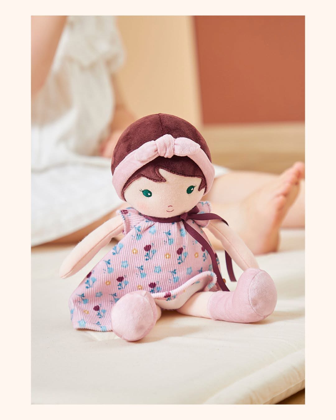 Boneca de pano com vestido rosa e padrão floral sentada