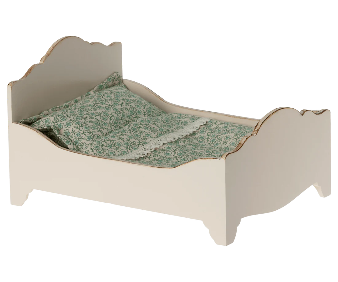 Cama pequena de madeira com roupa de cama floral verde e branca