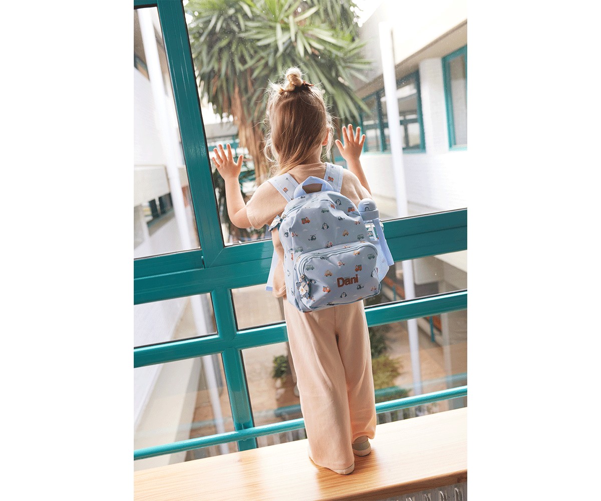 Criança com mochila azul clara com desenhos coloridos e nome Dani olhando pela janela