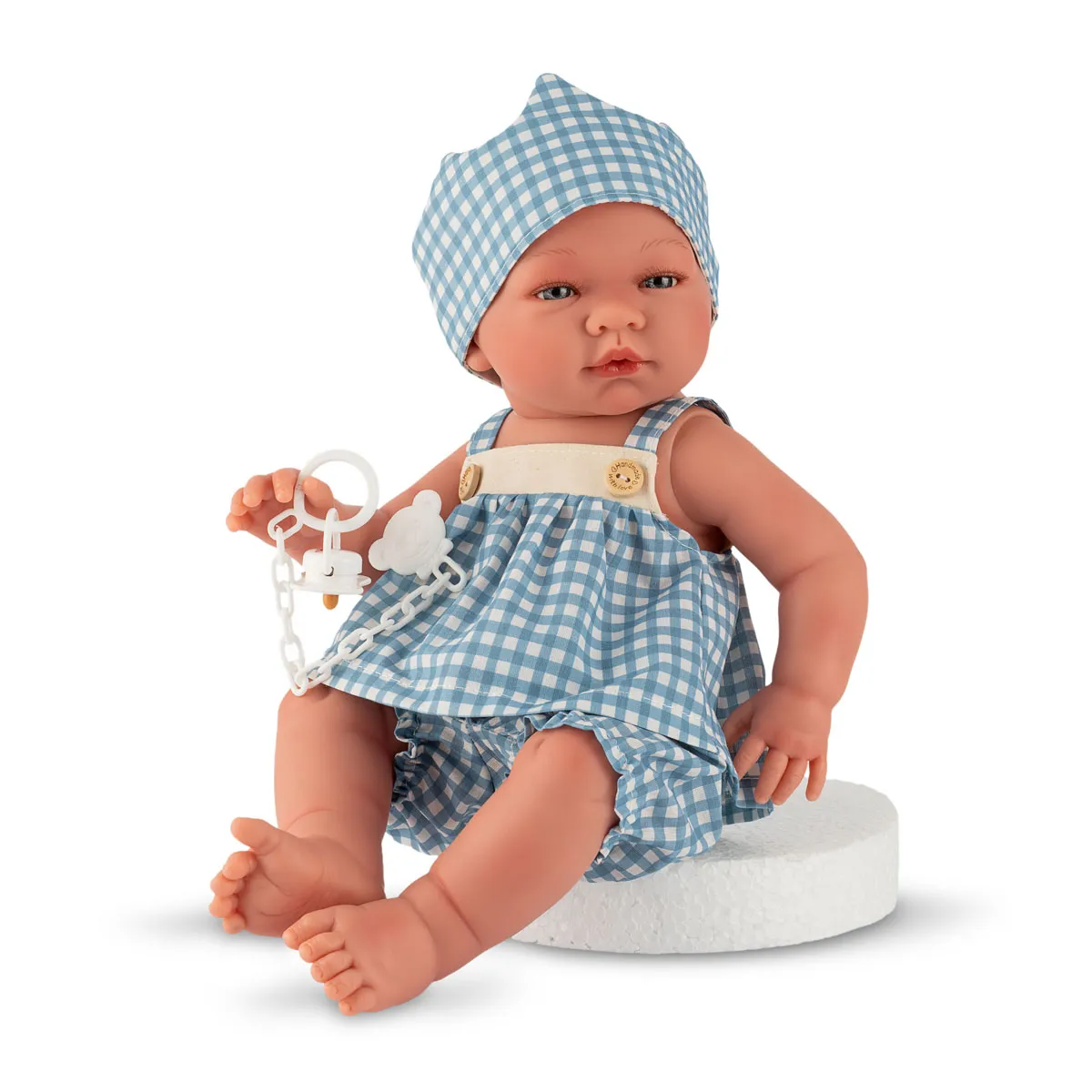 Boneca bebé com roupa azul às quadrículas brancas e prendedor de chupeta