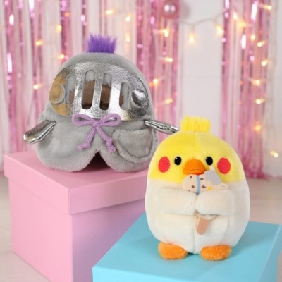 Peluches coloridos sobre caixas em cenário decorado com luzes e fitas cor-de-rosa.