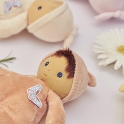 Bonecos de pelúcia com roupas de tecido macio em tons claros em superfície branca com flores