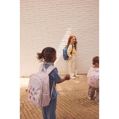 Crianças com mochilas coloridas perto de parede branca