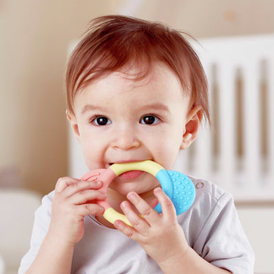 Bebé a morder brinquedo de dentição colorido num quarto de bebé