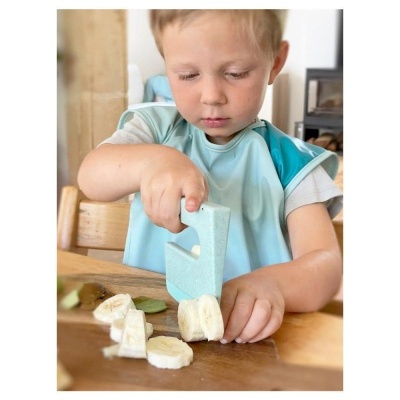 Criança a cortar banana com faca de plástico azul no interior