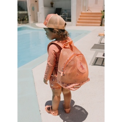 Criança com mochila e chapéu cor de salmão junto a piscina