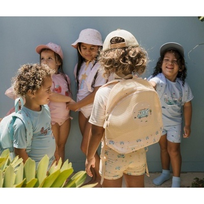 Cinco crianças com roupas coloridas e chapéus em espaço exterior com paredes azuis e plantas