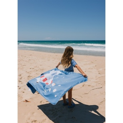 Criança na praia com toalha azul com desenho de urso branco e flores