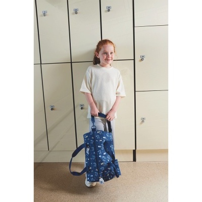 Criança com mochila azul floral em frente a armários escolares creme