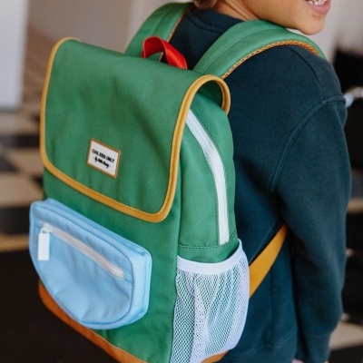 Criança com mochila verde com bolso azul claro e detalhes amarelos