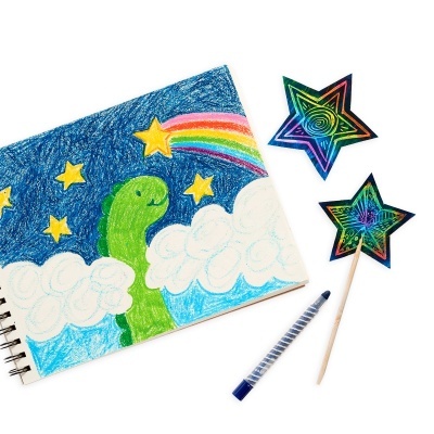 Caderno com desenho colorido de dinossauro e estrelas, caneta azul e estrelas holográficas em palito