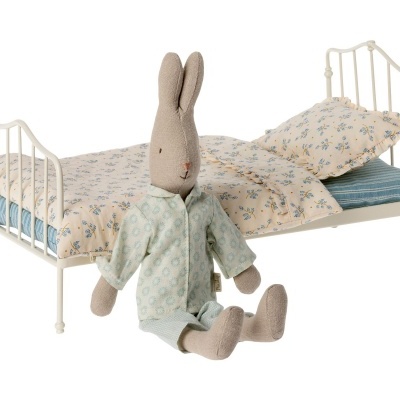 Cama infantil de metal com roupa de cama azul e branca e peluche de coelho vestido