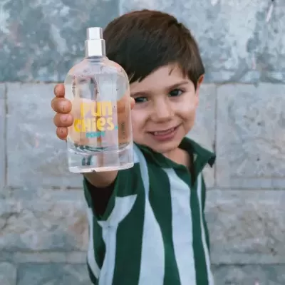 Menino a segurar garrafa spray transparente com texto amarelo e azul