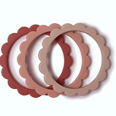 Três pulseiras de silicone onduladas em vermelho, rosa e bege sobre fundo branco