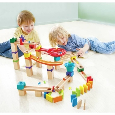 Crianças brincando com pista de bolas de madeira colorida no chão