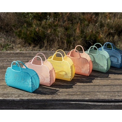 Seis malas pequenas coloridas com padrão perfurado alinhadas sobre madeira