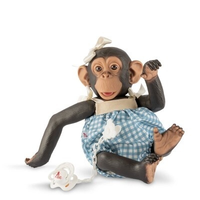 Boneca chimpanzé com vestido azul aos quadrados e fita na cabeça, com chupeta branca