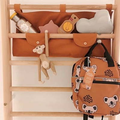 Bolsa organizadora castanha e mochila com padrão de ursos penduradas em estrutura de madeira clara