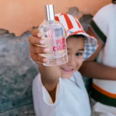 Garoto segurando frasco de perfume transparente com tampa prateada