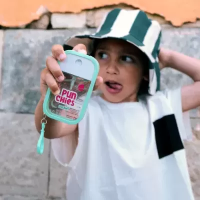 Criança com t-shirt branca e chapéu de riscas a segurar embalagem transparente PUN Chies