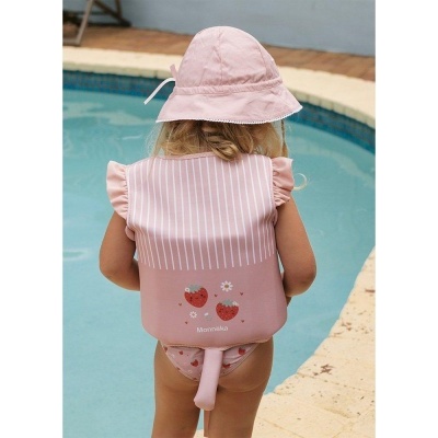 Criança de costas com colete salva-vidas rosa decorado e chapéu rosa junto à piscina