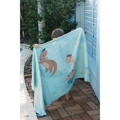 Criança segurando toalha azul claro com estampas de animais marinhos ao ar livre.