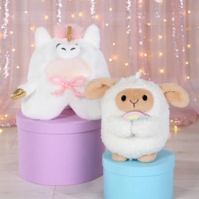 Peluches de unicórnio e ovelha sobre caixas redondas coloridas com fundo iluminado