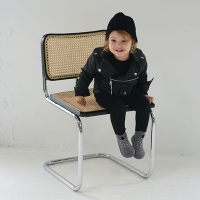 Cadeira metálica com assento e encosto em rattan natural com menino sentado
