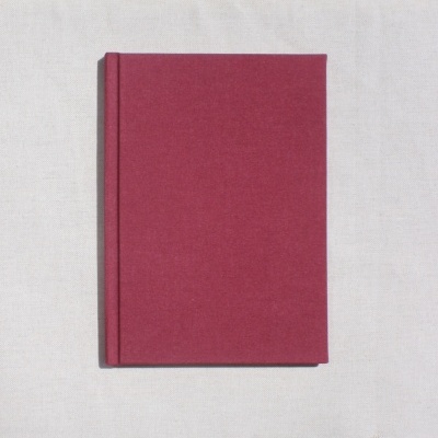 Livro de capa dura bordô sobre pano cru com textura