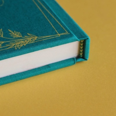 Livro com capa tecido verde esmeralda e detalhes dourados