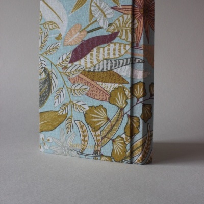 Capa de livro com tecido floral em tons pastel e padrão de folhas