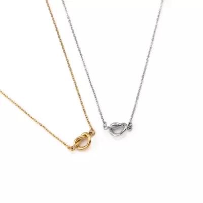 dois colares finos dourado e prateado com pendentes em nó entrelaçado em fundo branco