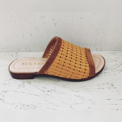 Chinelo aberto com padrão em tecido rattan amarelo e castanho sobre superfície branca