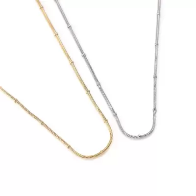 Duas correntes finas, dourada e prateada, em fundo branco