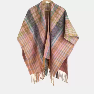 Xale ou poncho colorido com padrão em ziguezague e franjas pendurado num cabide de madeira