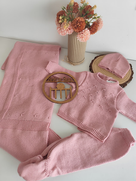 Conjunto de roupa de bebé cor-de-rosa com camisola, calças, gorro e manta em malha, apresentadas com vaso de flores decorativas