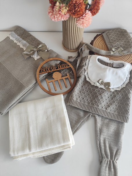 Conjunto de roupa de bebé em malha cinza com laço e gola branca, manta branca, flores e placa de madeira Bebé de Berço