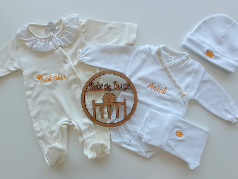 Conjunto de roupa de bebé creme e branco com bordados laranja e placa de madeira